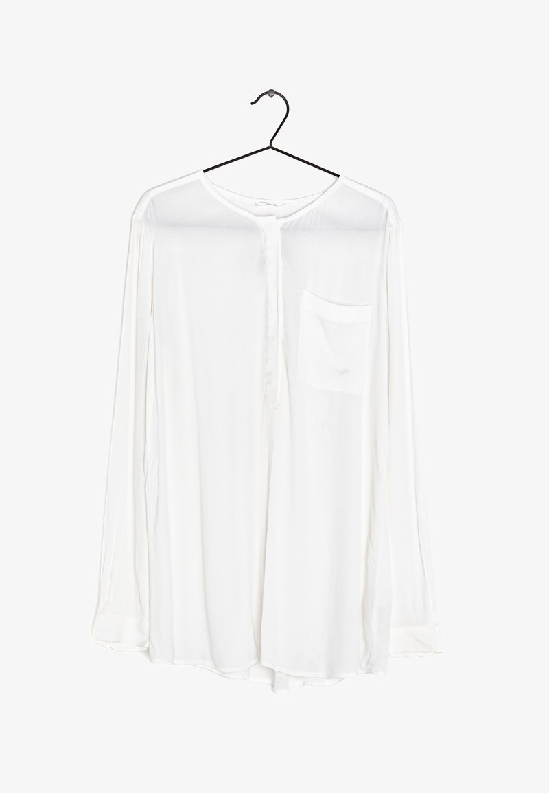 White long-sleeve shirt with a round neck, button front, a single breast pocket, and a soft, sheer fabric, hanging from a black hook.