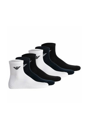 Six paires de chaussettes côtelées montantes en noir et blanc alternés, chacune avec un petit logo près du bord supérieur.