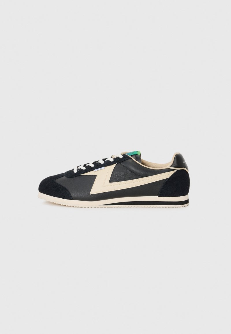 Black and beige sneakers featuring a leather and suede upper, rounded toe, textured accents, and white laces on a lightweight sole.