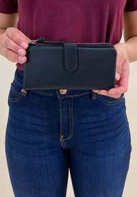 Black leather wallet with a textured finish, featuring a zipper closure and a snap button. Held in hands, displaying a sleek design.