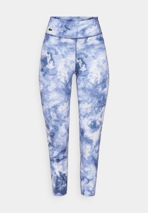 Fitted leggings in a blue tie-dye pattern, made of stretchy fabric. Features a wide waistband and a small brand logo on the front.
