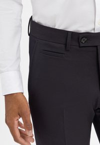 Dunkle, maßgeschneiderte Hosen aus glattem Stoff, mit flachem Frontdesign, einer Seitentasche und einem Knopfverschluss am Bund.