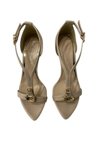 Sandali con tacco alto beige a punta, con un dettaglio in fibbia dorata e una fascia alla caviglia, realizzati in materiale sintetico liscio.