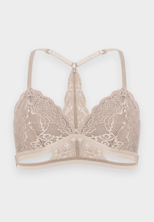 Braletă din dantelă bej cu modele florale, bretele reglabile și design racerback pe un fundal simplu, deschis.