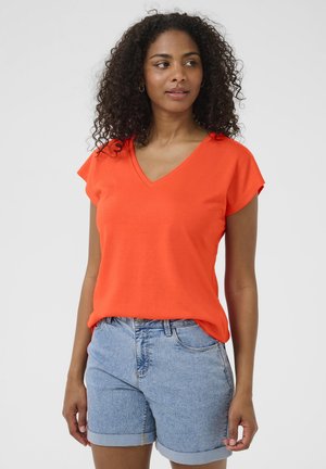 T-shirt à col en V et manches courtes en coton orange vif, associé à un short en denim bleu clair, avec des manches retroussées et une coupe classique.