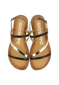 Sandalias negras con tiras y acentos metálicos plateados, con una suela plana color marrón claro y una hebilla ajustable en el tobillo, presentadas desde una vista superior.