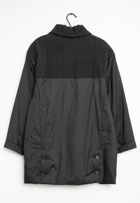 Svart jacka med en texturerad, mönstrad övre del. Har en vikbar krage och knappdetaljer vid ärmsluten och nederkanten. Slät tyg.