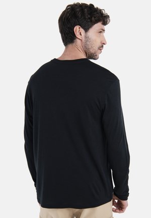 Sort langærmet skjorte med rund hals og blød tekstur, der har en afslappet pasform og minimale syninger på ryggen.