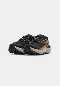 Chaussures de trail running noires et orange avec une surface texturée, présentant un design incurvé, une semelle extérieure agressive et un système de laçage intégré.