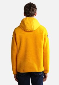 Yellow fleece jacket with textured surface, attached hood, and back seam detailing; features a small logo on the left sleeve.