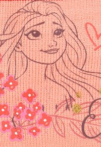 Pink knitted fabric featuring a character illustration, surrounded by colorful flower designs in red and pink with glitter accents.