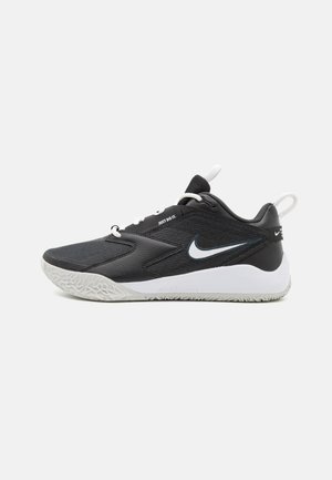 Chaussure de sport Nike noir et blanc avec logo Swoosh blanc, semelle rembourrée et languettes sur la languette et le talon.