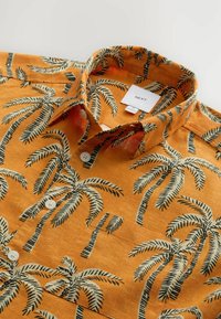 Kurze Ärmel, orangefarbener Hemd mit Palmbaum-Muster. Verfügt über einen Button-Down-Kragen, weiße Knöpfe und ein Stoffetikett mit der Marke "NEXT."
