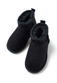 Stivaletti neri in suede con una morbida fodera interna e un tirante sul retro. Il design include una punta arrotondata e accenti cuciti.