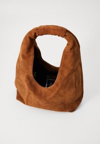 Brown suede handbag with a slouchy shape, a rounded handle, and an open top. Features a soft texture and a pocket with a zipper inside.