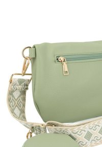 Borsa in ecopelle verde con chiusura a zip, dotata di una tracolla decorata in crema e verde. Include dettagli in metallo dorato.