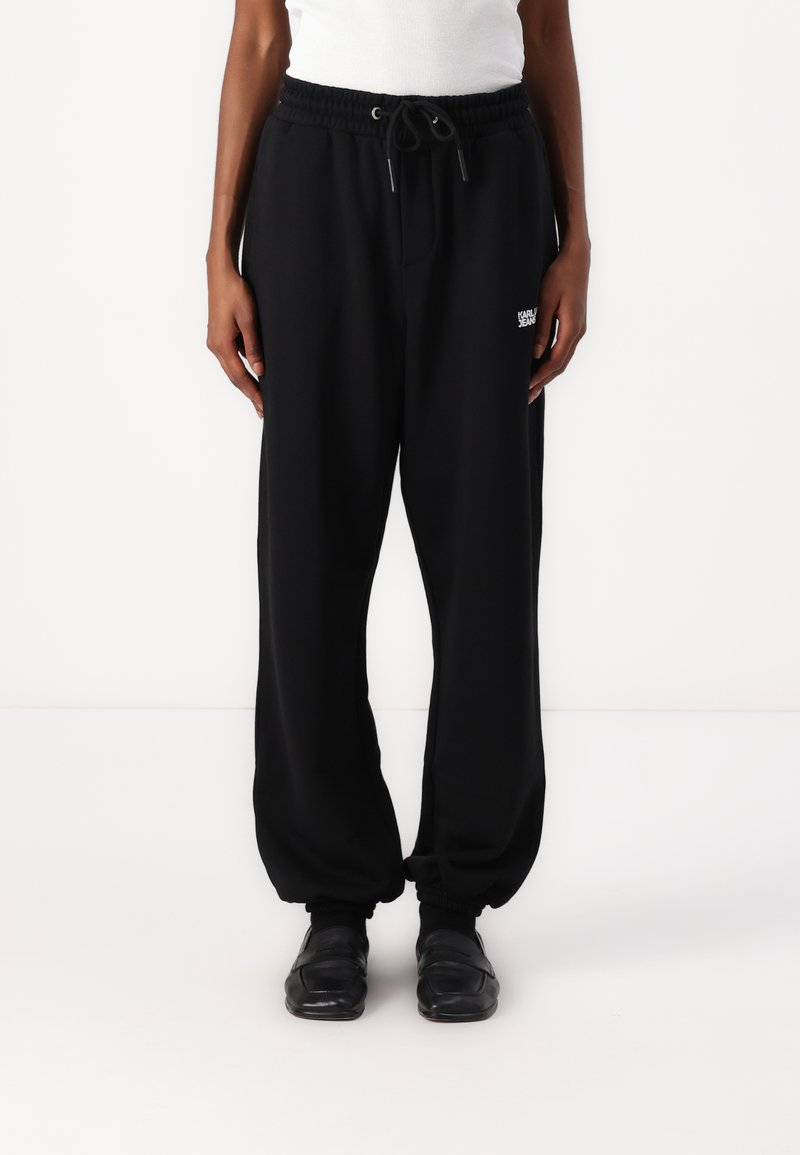 Pantaloni sportivi neri con cintura elastica e cordoncino. Caviglie con polsini e piccolo dettaglio logo bianco sulla parte superiore della gamba sinistra. Tessuto morbido.