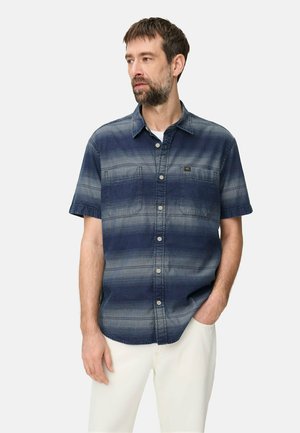 Man wearing a short-sleeve blue gradient striped button-up shirt with two chest pockets and white pants, standing against a plain background.