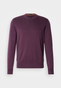 Pull homme à manches longues col rond unicolore violet foncé avec poignets et bas côtelés, avec un petit logo patché sur la poitrine.