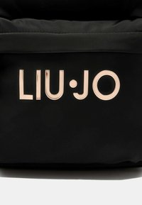 Borsa nera in nylon con un logo "LIU·JO" in evidenza color rosa oro. La texture è liscia con una finitura opaca. Design semplice e moderno.
