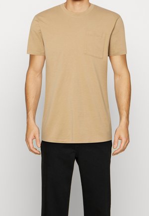 Beige T-shirt met korte mouwen en een ronde hals, voorzien van een enkele borstzak, gemaakt van soepele stof, weergegeven tegen een lichte achtergrond.