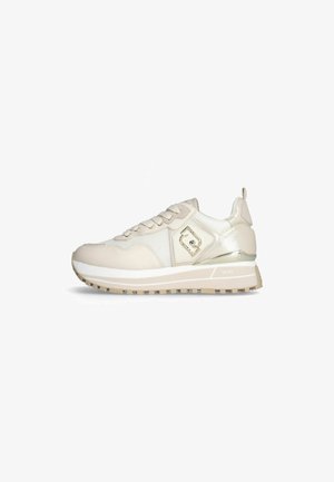 Chaussure de sport beige avec une tige en mesh texturé et cuir lisse, présentant un accent métallique et une semelle en caoutchouc épaisse et à motifs.