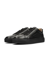 Baskets en cuir noir avec finition texturée, lacets plats noirs, semelle en caoutchouc et un accent logo subtil sur le côté. Design de bout arrondi.