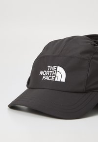 Crna bejzbol kapa izrađena od sintetičkog materijala. Ima zakrivljeni vizir i logo "The North Face" u bijeloj boji na prednjem panelu.