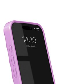 Violeta plastikā izgatavota telefona soma ar spīdīgu apdari, turklāt tajā ir melns ekrāns, kas rāda laiku un datumu, kā arī redzami sānu pogas.