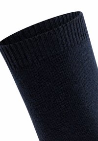 Calza lavorata a maglia di un blu navy scuro con dettaglio a costine nella parte superiore, presentata in primo piano su uno sfondo bianco.