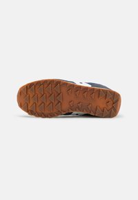 Navy running shoe outsole with a textured, brown rubber sole featuring a triangular tread pattern and the brand name “Saucony” embossed.