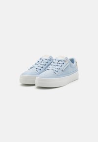 Baskets en toile bleu clair avec une semelle en caoutchouc blanche, bout rond, six oeillets et un logo discret sur la languette et sur le côté.