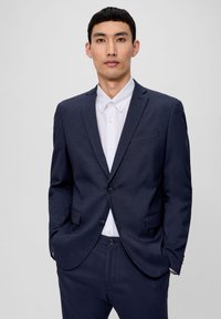 Marineblauer Anzug mit glatter Textur, einreihiger Jacke, Reverskragen und passender Hose über einem weißen Hemd mit Kragen.