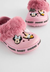 Roosa puukingad pehme ülemiseosaga, millel on Minnie Mouse'i ja Daisy Duck'i karakteri disain. Hambuline pöial ja trükitud tekst ümber aluse.