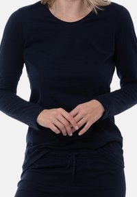 Maglietta blu navy a maniche lunghe con scollatura rotonda. Tessuto morbido e elasticizzato con vestibilità casual e polsini arrotolati. Abbinata a pantaloni coordinati.