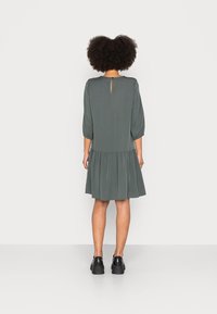 Vestido de manga corta y largo hasta la rodilla en verde oliva, con falda de volantes, corte en forma de llave en la parte posterior y puños de manga elásticos.