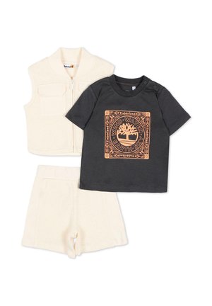 Trzyczęściowy strój dla malucha, składający się z beżowej dzianinowej kamizelki i szortów oraz czarnej koszulki z krótkim rękawem z pomarańczowym logo Timberland i motywem przyrodniczym.