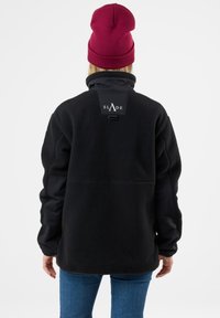 Giacca in pile nera con colletto e maniche in nylon nero a contrasto. Caratterizzata da una toppa con logo sul retro e una vestibilità morbida.
