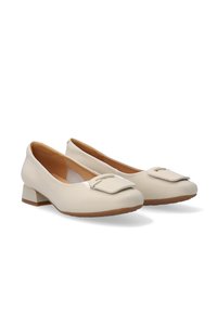 Beige patent leather flats with a square toe, decorative buckle accent, and a small block heel. Smooth texture and rounded silhouette.