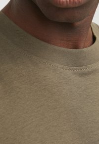 Olivengrøn bomulds t-shirt med ribbet rund hals og glat tekstur, med fokus på halsudskæringen og de øverste stofdetaljer.