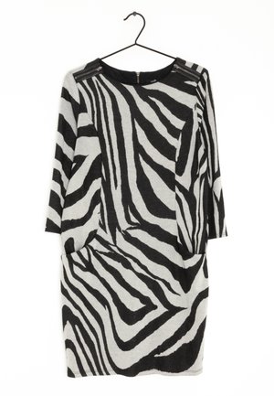 Schwarz-weiß gestreiftes Kleid mit Zebra-Muster, dreiviertel Ärmel, runder Ausschnitt und zwei seitlichen Taschen. Verfügt über einen Reißverschluss an den Schultern.