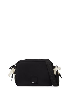 Geantă neagră dreptunghiulară de purtat pe umăr, cu detalii albe de șnur, curea reglabilă cu numele brandului în relief și patch cu logo-ul frontal.