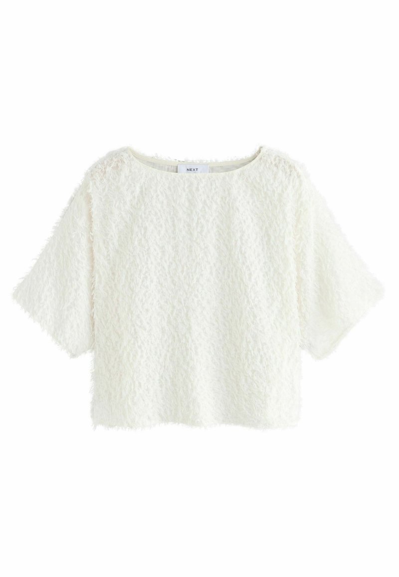 Top corto bianco realizzato in un tessuto morbido e fluffy, con maniche corte e scollo rotondo. Etichetta visibile al centro sul retro.