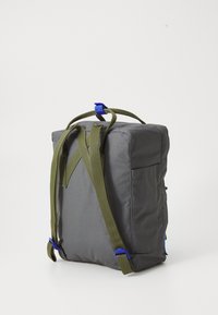 Grå stoffryggsekk med olivengrønne stropper, et blått akcent, rektangulær form, og en sidelomme. Jevn tekstur, enkel design.