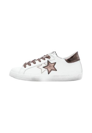 Sneaker bassa bianca con stella e tab sul tallone in bronzo metallico, lacci in stampa leopardata e suola bianca leggermente usurata.
