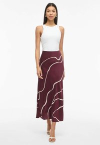 Burgundy maxi nederdel med flydende form, prydet med hvide bølgede linjemønstre; parret med en tætsiddende hvid tanktop for et afslappet look.