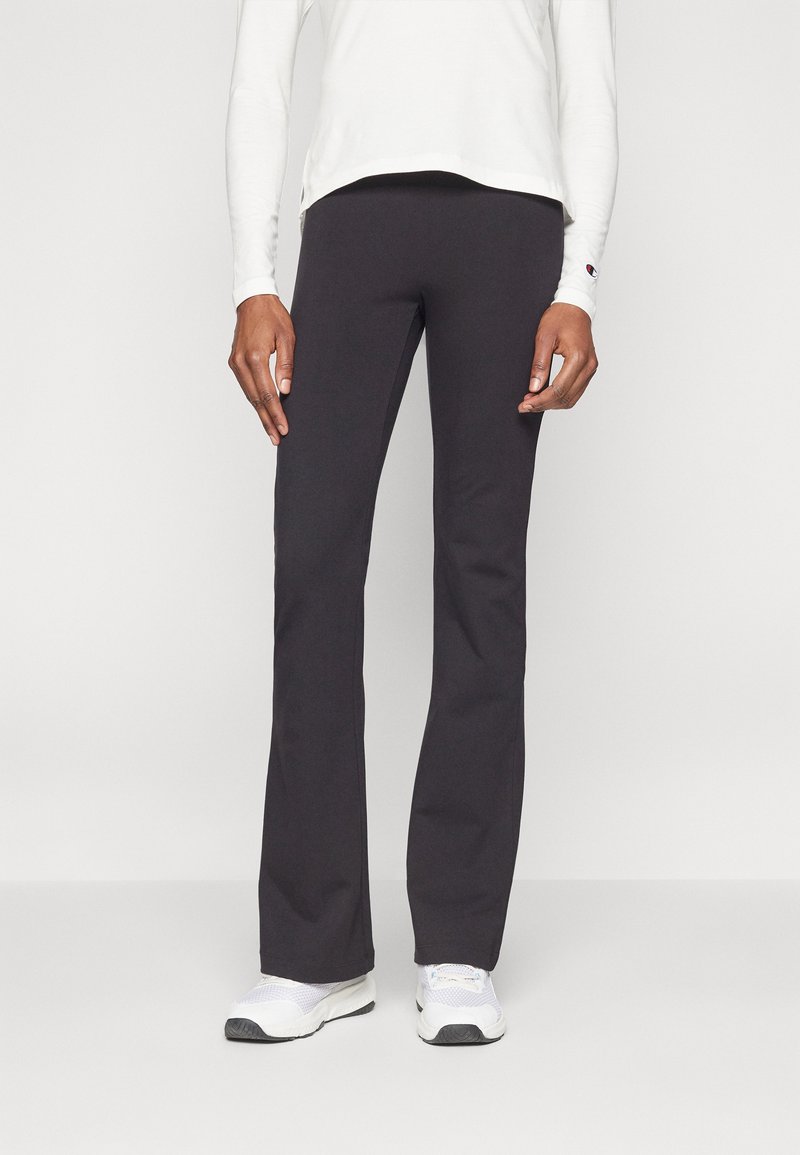 Svarta sportbyxor med rak passform, tillverkade av mjukt tyg. Bärs med en långärmad vit topp och vita sneakers.