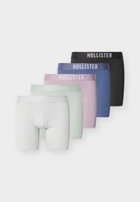 Cinq paires de boxers pour hommes Hollister en blanc, vert clair, rose clair, bleu et noir, disposées en pile décalée.
