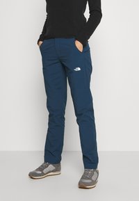 Marinblå utomhusbyxor med slim fit, med framfickor och en vit logotyp på låret; tillverkade av ett hållbart, lätt material.