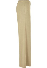Pantalon beige coupe décontractée avec taille élastique et poches latérales, présenté de profil sur fond blanc.